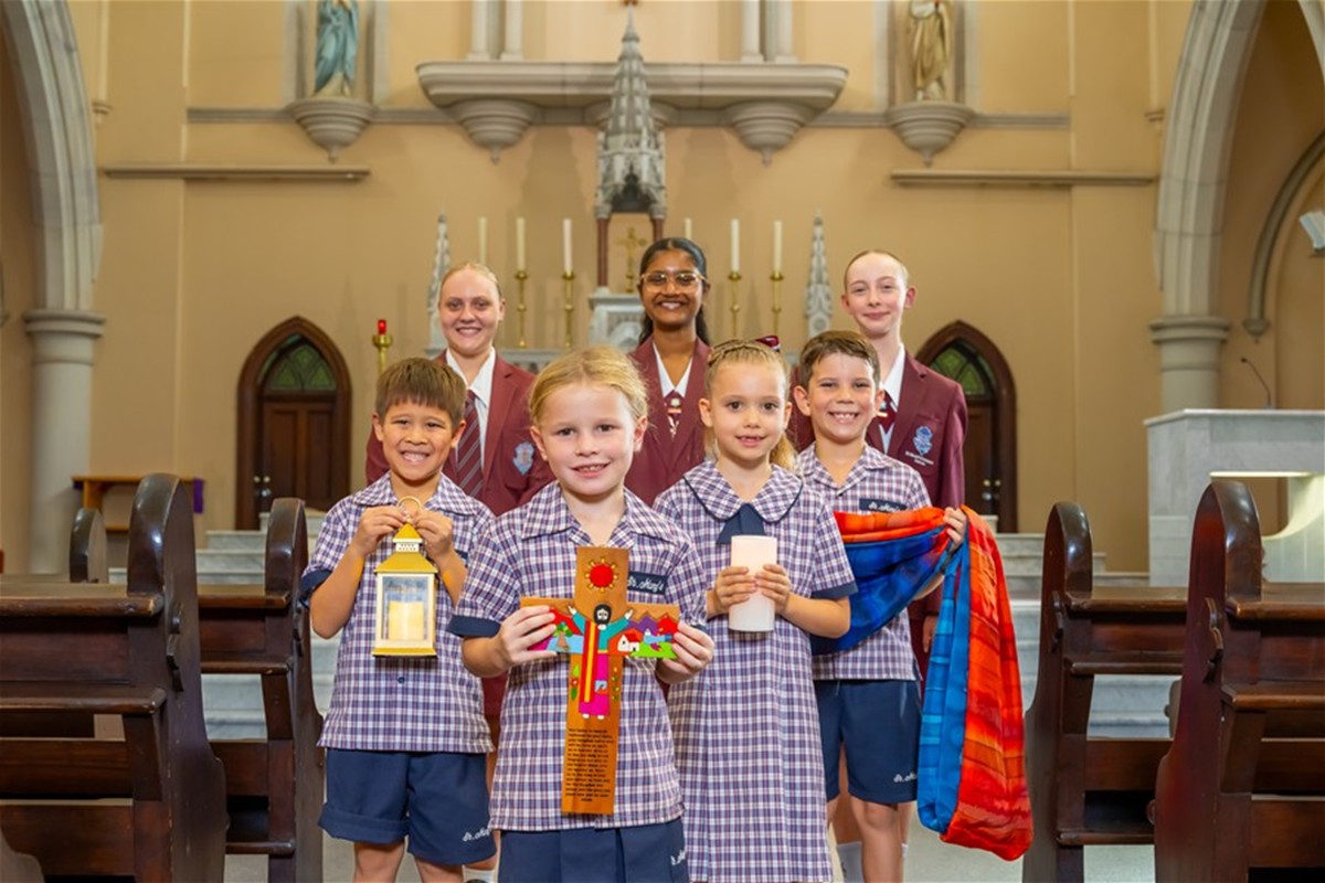 Students of St Mary's Ipswich holding cross and candles in front of altar in church